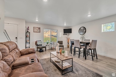 Living room with plenty of natural light, light wood-style floors, and recessed lighting
