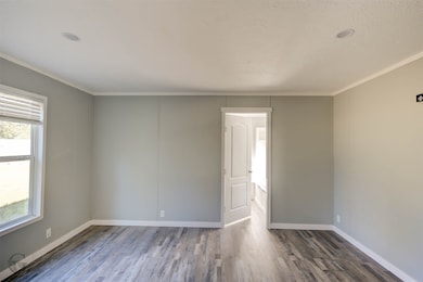Unfurnished room with wood finished floors and crown molding