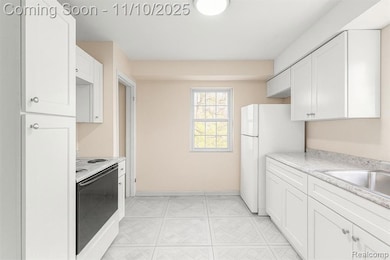 Kitchen with electric stove, freestanding refrigerator, and white cabinets