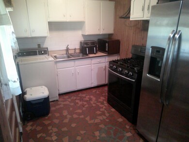 Kitchen with black appliances, washer / dryer, sink, decorative backsplash, and white cabinets