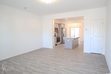Unfurnished living room with light wood finished floors, baseboards, a sink, and a chandelier
