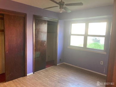 unfurnished bedroom featuring two closets, wood finished floors, and ceiling fan