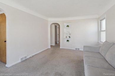 Living area featuring arched walkways, built in features, and carpet