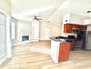 Kitchen featuring dark countertops, ceiling fan, a peninsula, stainless steel appliances, and lofted ceiling