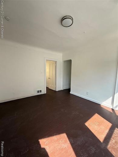 Unfurnished room featuring dark wood finished floors and arched walkways