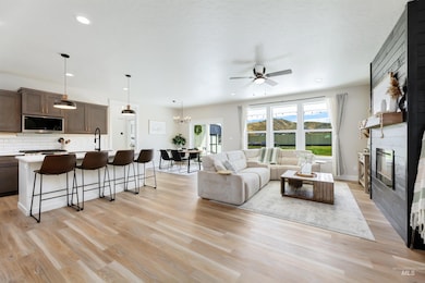 Living room with ceiling fan, a fireplace, light wood-style flooring, recessed lighting, and a chandelier