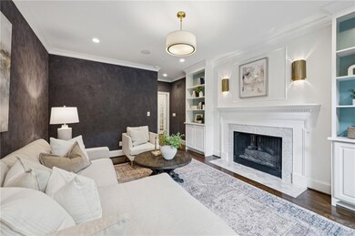 Living room with crown molding, a high end fireplace, recessed lighting, dark wood-type flooring, and built in shelves