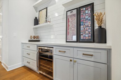 A bar enclave with a beverage refrigerator and ope