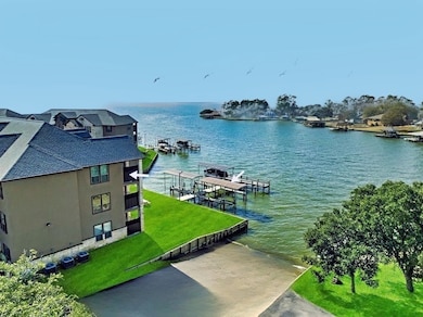 This photo showcases a waterfront property with a multi-story building featuring balconies overlooking a serene body of water. The area includes private docks, lush green lawns, and scenic views of the waterway, ideal for boating and relaxation.