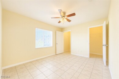 Unfurnished bedroom with a spacious closet, light tile patterned flooring, and a ceiling fan