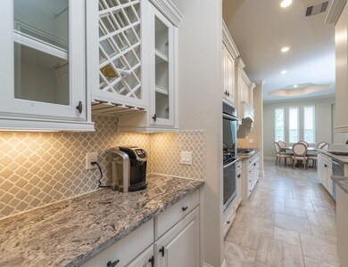 View of the butler's pantry with built-in wine rack and stemware holder.  Note the beautiful granite!