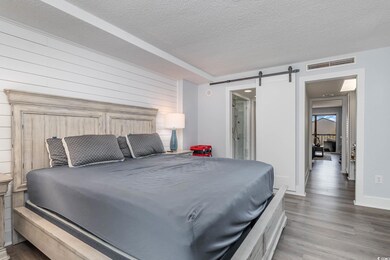 Bedroom featuring a barn door, a textured ceiling,