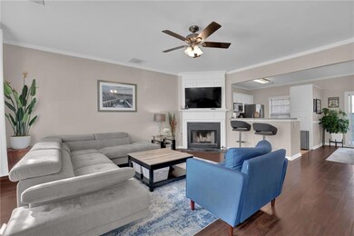 Living room with ornamental molding, ceiling fan, dark wood finished floors, a large fireplace, and baseboards