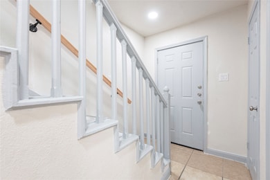 Entrance foyer with stairway, light tile patterned flooring, and recessed lighting