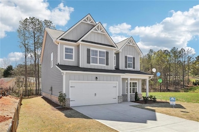 Craftsman-style house with board and batten siding, an attached garage, concrete driveway, and a front yard