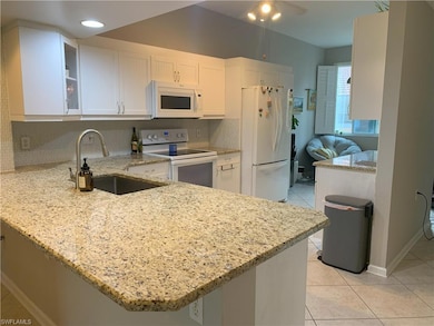 Kitchen with a peninsula, white appliances, a sink