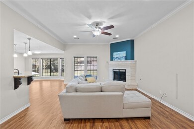 Living area with ornamental molding, light wood-style floors, a stone fireplace, ceiling fan, and recessed lighting