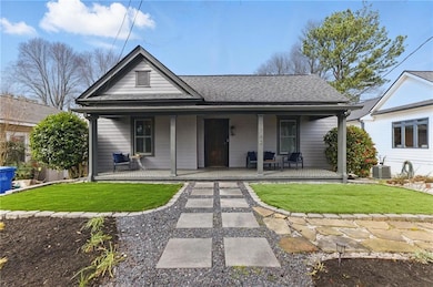 View of front facade with a front lawn, roof with shingles, and a porch