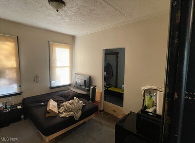 Carpeted bedroom featuring a textured ceiling and ornamental molding