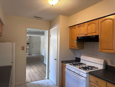 Kitchen featuring white appliances, dark countert