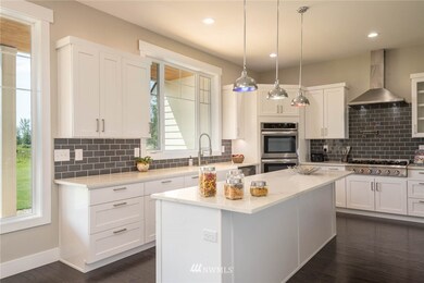 Gorgeous modern kitchen withh quartz counters,large 4 person Island,glass subway tile back splash,ss appliances double oven,garden sink,brushed nickle pendant lighting,walk in panty,commercial size gas range and of course water feature above stove for easy cooking.  All this with views of large back yard and Mount Rainier to the south east
