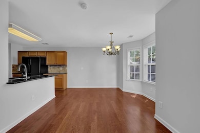 Kitchen with freestanding refrigerator, dark wood-style flooring, dark countertops, a chandelier, and tasteful backsplash