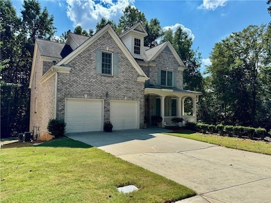 View of front facade featuring a porch, brick siding, concrete driveway, and a front lawn