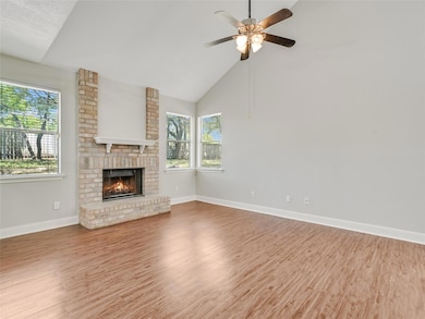 Unfurnished living room with light wood-style flooring, high vaulted ceiling, a brick fireplace, and a ceiling fan