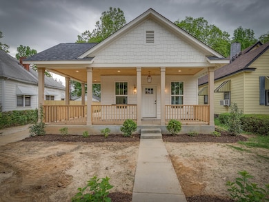 View of front of house featuring a porch, a shingled roof, and cooling unit