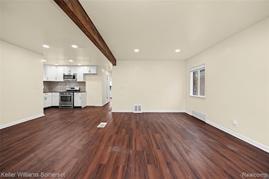 Unfurnished living room featuring beamed ceiling, dark wood-style flooring, and recessed lighting