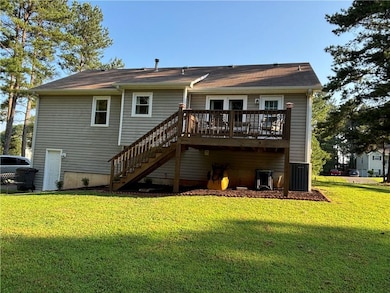 Back of property with stairway, a wooden deck, and a lawn