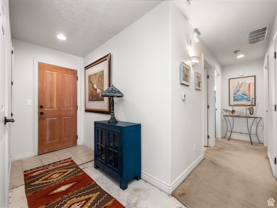 Foyer entrance with recessed lighting, a textured ceiling, and light tile patterned floors