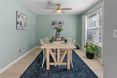 Dining space with light wood finished floors, a textured ceiling, and ceiling fan