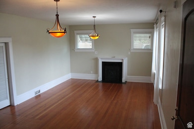 Unfurnished living room with the original hardwood floors, healthy amount of natural light, and a fireplace (not used) with flush hearth