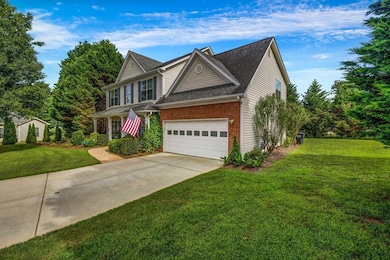 Traditional-style house with brick siding, concrete driveway, a front yard, and an attached garage