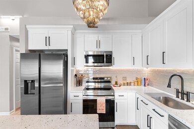 Kitchen featuring appliances with stainless steel finishes, a sink, light stone counters, and tasteful backsplash