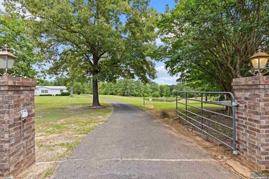 View of asphalt driveway with a gate and view of wooded area
