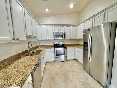 Kitchen with stone counters, sink, vaulted ceiling