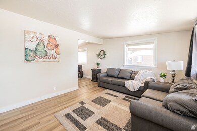 Living area featuring light wood-style floors, a textured ceiling, and vaulted ceiling