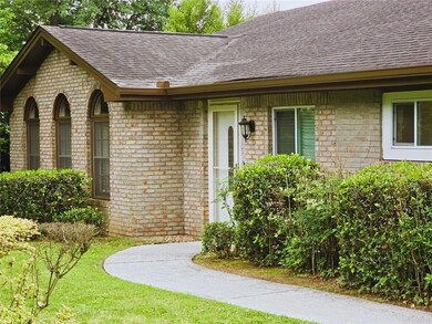 Property entrance featuring roof with shingles, brick siding, and a yard