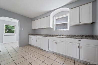 Kitchen featuring arched walkways, white cabinetry, and white dishwasher