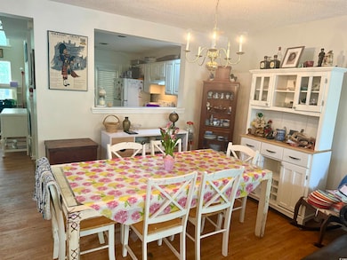 Dining area with wood finished floors, a textured ceiling, and a chandelier