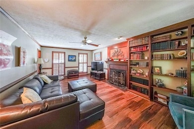 Living room featuring a ceiling fan, a textured ce