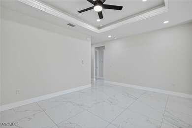 Spare room featuring light marble finish flooring, a tray ceiling, recessed lighting, ornamental molding, and ceiling fan