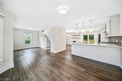 Kitchen featuring dark hardwood floors, backsplash, light countertops, stainless steel fridge, plenty of natural light, and pendant lighting