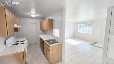 Kitchen with white electric range oven, a sink, under cabinet range hood, black dishwasher, and light tile patterned floors