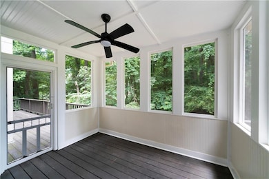 Unfurnished sunroom featuring ceiling fan and hardwood / wood-style floors