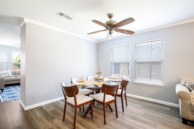Dining room featuring a textured ceiling, a ceiling fan, wood finished floors, and crown molding
