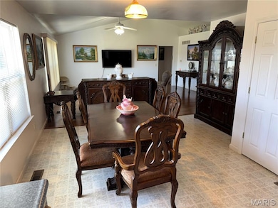 Dining space featuring vaulted ceiling, light floors, and ceiling fan