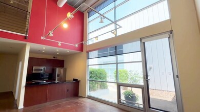 Kitchen featuring appliances with stainless steel finishes, a towering ceiling, and dark countertops